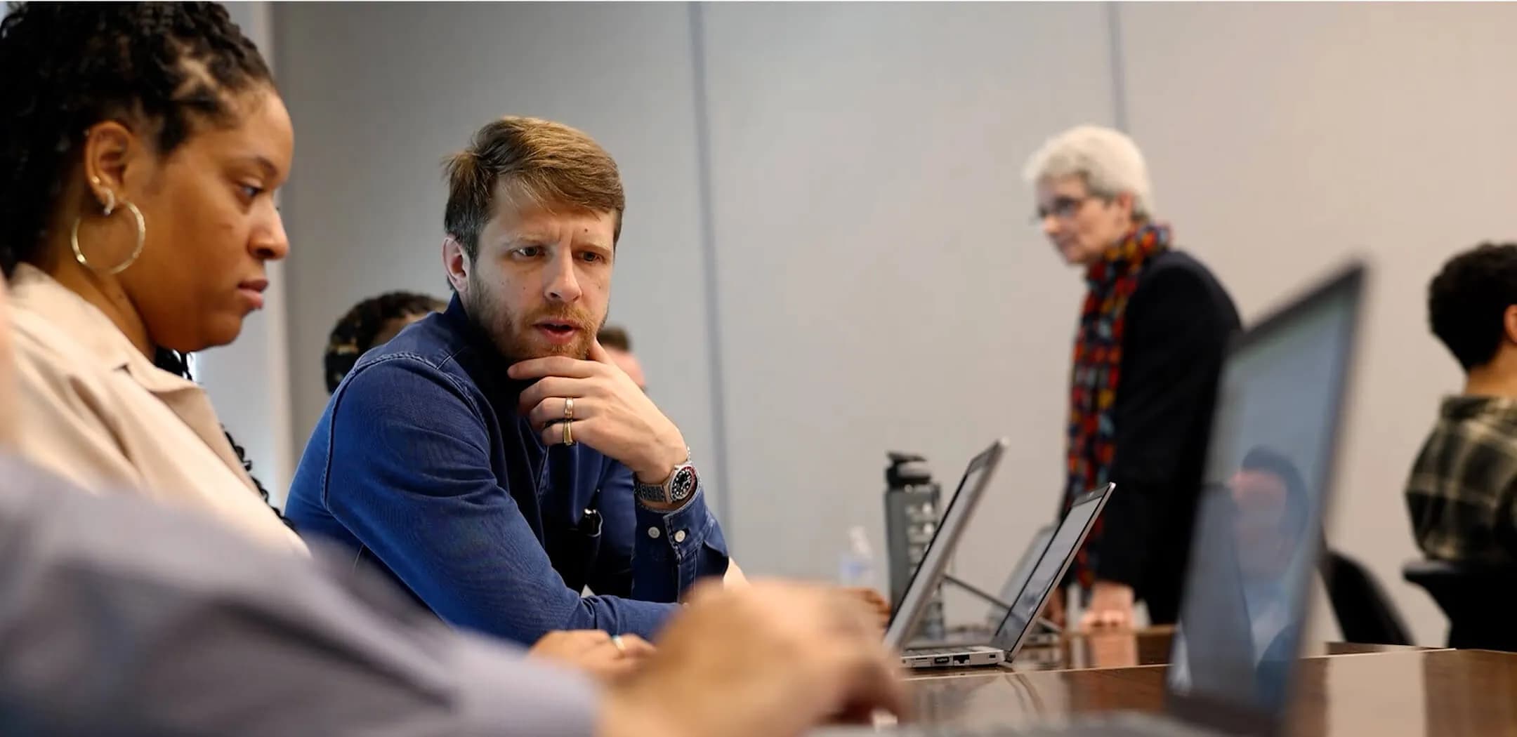 Man and women sitting at laptop in a class.