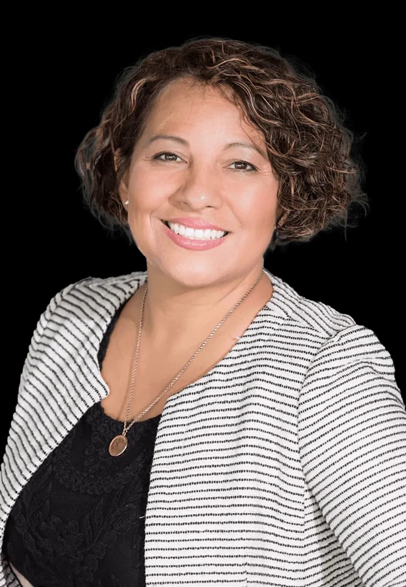 Woman in business casual attire smiling towards camera.